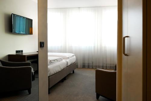 a bedroom with a bed and a tv and a window at Sylter Hof Berlin in Berlin