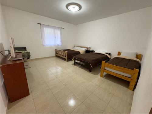 a room with two beds and a television in it at Suarez home in Puerto Madryn