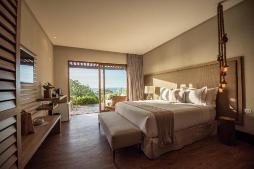 a bedroom with a large bed and a balcony at Colina Pousada SPA in Fernando de Noronha