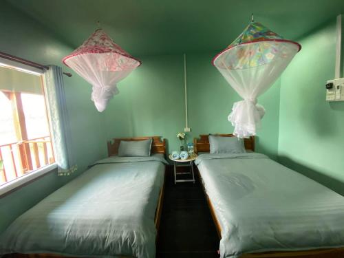 two twin beds in a room with two windows at Don Det SODA RiverSide Guesthouse in Ban Donsôm Tai