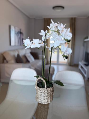 a vase with white flowers on a table in a living room at SunGolf Apartment in Los Alcázares