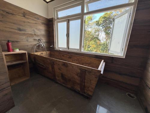 a large wooden bath tub in a room with a window at Paljor Farm in Ravangla