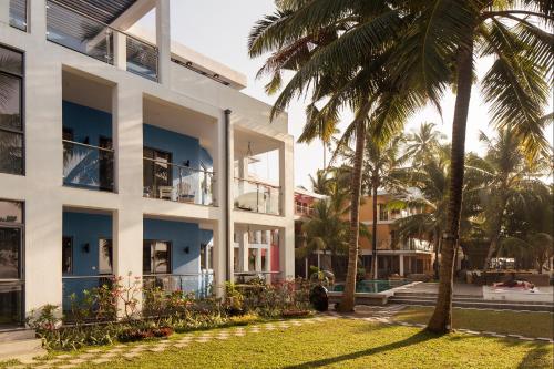 a building with palm trees in front of it at Owl and the Pussycat Hotel & Restaurant in Unawatuna