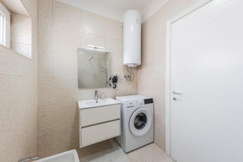 a bathroom with a washing machine and a sink at Coastal Haven Talea by PikHost in Tale