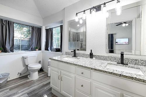 a white bathroom with two sinks and a toilet at Little House in the Prairie in Grand Prairie