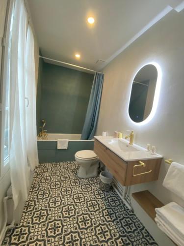a bathroom with a sink and a toilet and a tub at Hotel Boileau in Paris