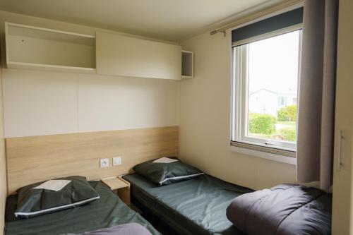 a small room with two beds and a window at Camping Pomme de Pin in Stella-Plage