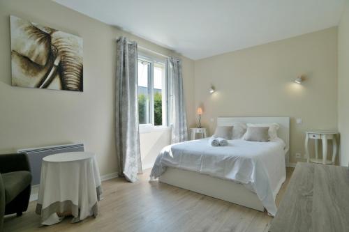 a white bedroom with a bed and a window at Spacieuse maison avec piscine proche plage à Canca in Cancale