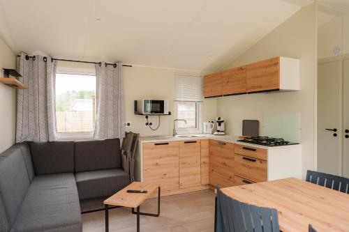 a kitchen and living room with a couch and a table at Camping Pomme de Pin in Stella-Plage
