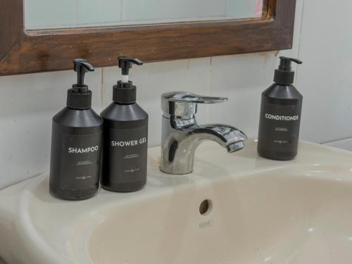 three bottles of soap sitting on a bathroom sink at Dream Stay Green in Nuwara Eliya