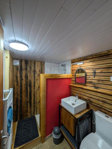 a bathroom with a white sink and a red wall at Chambre d'hôtes Chalet AILLEURS in Molines-en-Queyras