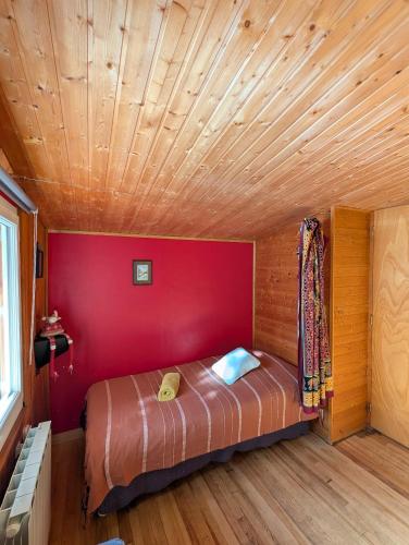 a bed in a room with a red wall at Chambre d'hôtes Chalet AILLEURS in Molines-en-Queyras