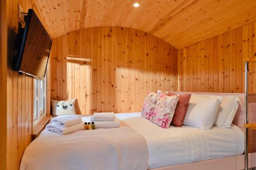 a large bed in a room with wooden walls at Finest Retreats - Demelza Shepherds Hut in Grade