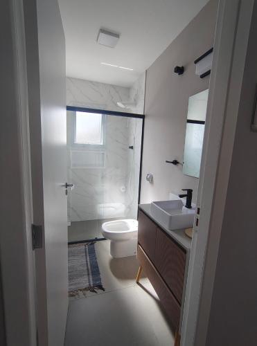 a white bathroom with a toilet and a sink at Refúgio leve no Campeche in Florianópolis
