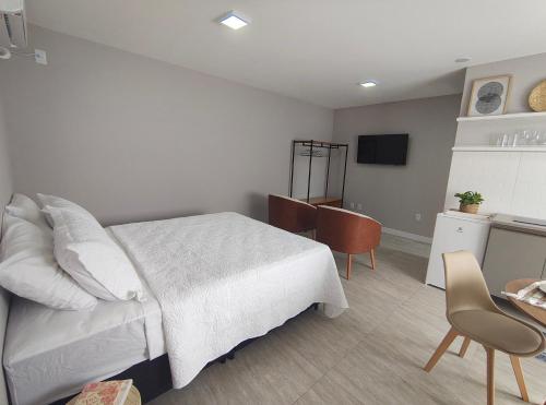 a bedroom with a white bed and a table at Refúgio leve no Campeche in Florianópolis
