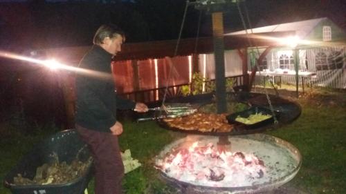 a man cooking food on a grill at night at Gästehaus-Weingut Michael Scholer in Schleich