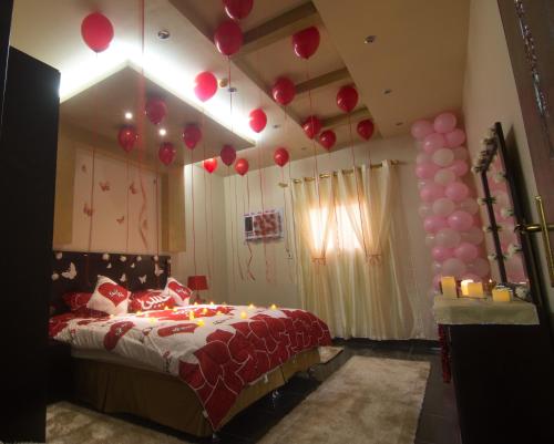 a bedroom with a bed with balloons hanging from the ceiling at Qsr Al Lolo in Sakakah