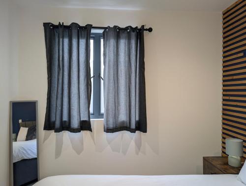 a bedroom with a bed and a window with curtains at Two Bedroom Flat with Ensuite Bathrooms in Hemel Hempstead