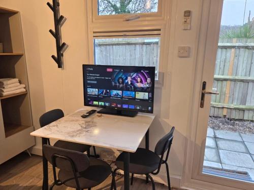 a desk with a computer on a table with chairs at Secret Garden Studio in Eltham