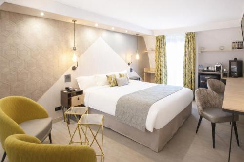 a hotel room with a bed and two chairs at Best Western Plus Opéra Batignolles in Paris