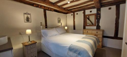 a bedroom with a white bed and a wooden ceiling at Whitewells Farm Cottages - 7 exceptionally well appointed pet friendly barn conversions set in 10 acres of gardens, fields and woodland suitable from 2 to 24 people with breathtaking views towards the Malvern Hills, Herefordshire and Worcestershire in Mathon