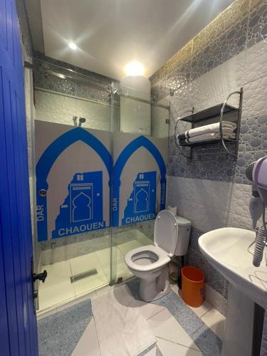 a bathroom with a shower with a toilet and a sink at Hotel Annasr in Chefchaouen