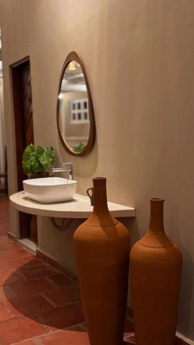 two vases sitting on a bathroom counter with a mirror at Pousada Vila Bacana in São Miguel do Gostoso