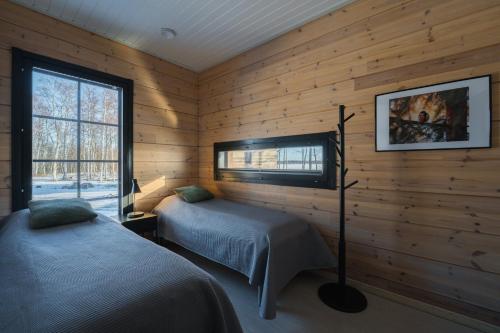 two beds in a room with wooden walls and a window at Iisland Aava in Ii