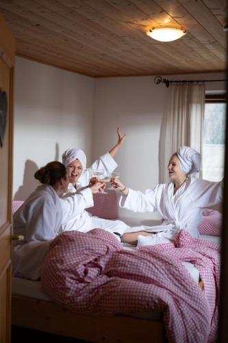 three people dressed in white are sitting on a bed at BuchackerAlm -1,5h panoramic walk in Angerberg