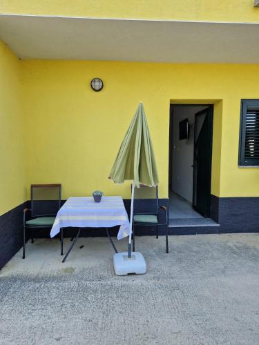 a table with an umbrella next to a yellow wall at Sunce 5 in Vrbnik