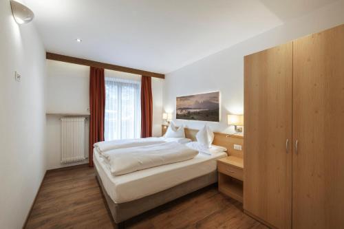 a bedroom with a bed and a large window at La Tambra - Residence - Central with Restaurant in Santa Cristina Gherdëina