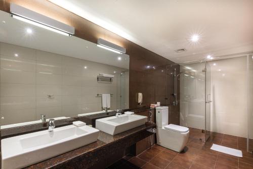 a bathroom with two sinks and a toilet and a mirror at Turyaa Kalutara in Kalutara