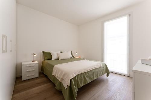 a white bedroom with a bed and a window at Dama Apartments in San Vito di Leguzzano