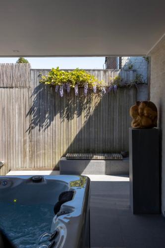 a hot tub sitting on a patio with a fence and flowers at Vakantiewoning Relax Ohm in Zottegem