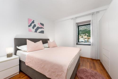 a bedroom with a bed with pink pillows and a window at Apartment Alen in Makarska