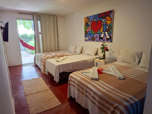 a room with two beds and a painting on the wall at Pousada dos Mundos1 in Conde