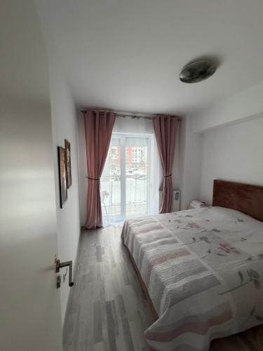 a bedroom with a bed and a large window at Favorite Apartmet in Braşov