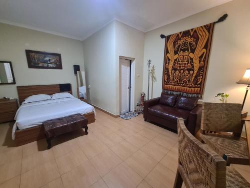 a bedroom with a bed and a leather chair at Comfy Room Yogyakarta BY Hamsa Putih in Yogyakarta