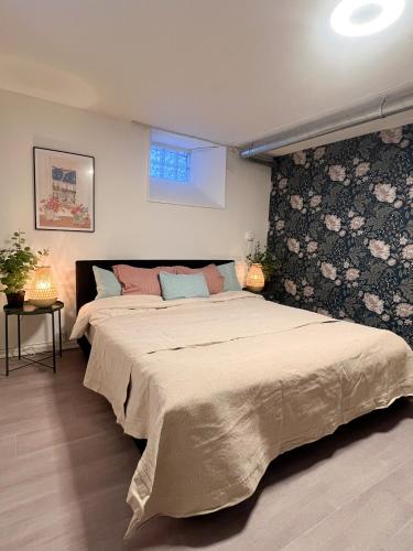 a bedroom with a large bed and a floral wall at Skolmästarevägen Åldersgräns 30 in Falun