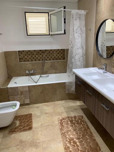 a bathroom with a tub and a sink and a bath tub at Villa haut-standing avec piscine à Hammamet in Yasmine