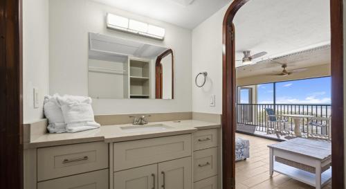 a bathroom with a sink and a mirror and a balcony at Mariner's Boathouse and Beach Resort by CoolVacay in Fort Myers Beach