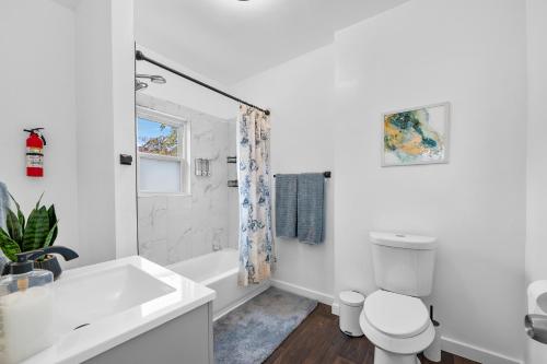 a white bathroom with a tub and a toilet at Quiet Detroit 3BR | Near Downtown + WiFi in Detroit