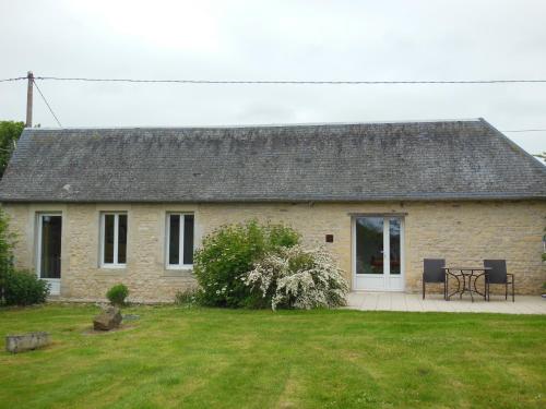 a stone house with a table and chairs in a yard at Gîte La Buhennerie 2 personnes in Longues-sur-Mer