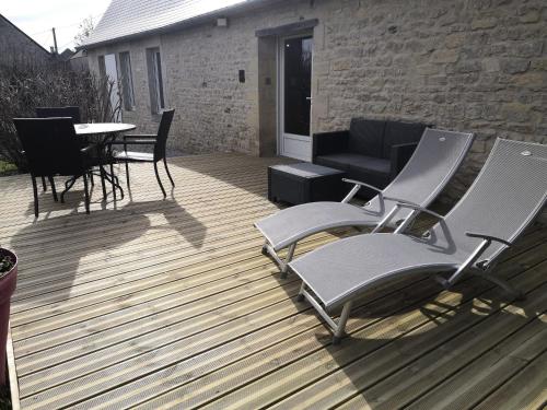 a deck with chairs and a table and a couch at Gîte La Buhennerie 2 personnes in Longues-sur-Mer