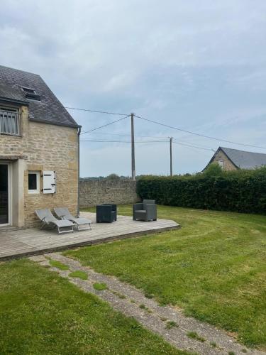 a patio with two lounge chairs and two speakers at Gîte Le Val de Marigny 2 personnes in Longues-sur-Mer