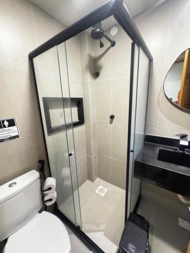 a small bathroom with a toilet and a shower at Suítes Viver Arraial do Cabo in Arraial do Cabo