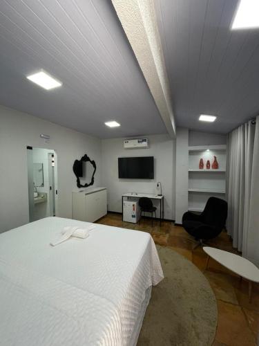 a bedroom with a white bed and a tv at Aiezza Hotel in Barcarena