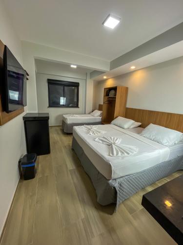 a hotel room with two beds and a television at Pousada Arco Iris Fortaleza in Fortaleza