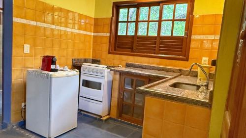 a kitchen with a sink and a stove at Pousada Taman Baru in Pirenópolis