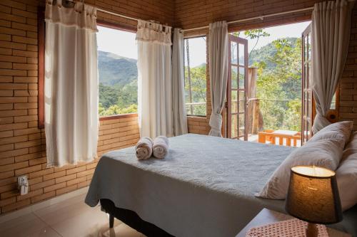 a bedroom with a bed with two towels on it at Casa Mohini Refúgio nas montanhas de Teresópolis Quarto com deck rede suspensa, lareira e cachoeira in Teresópolis